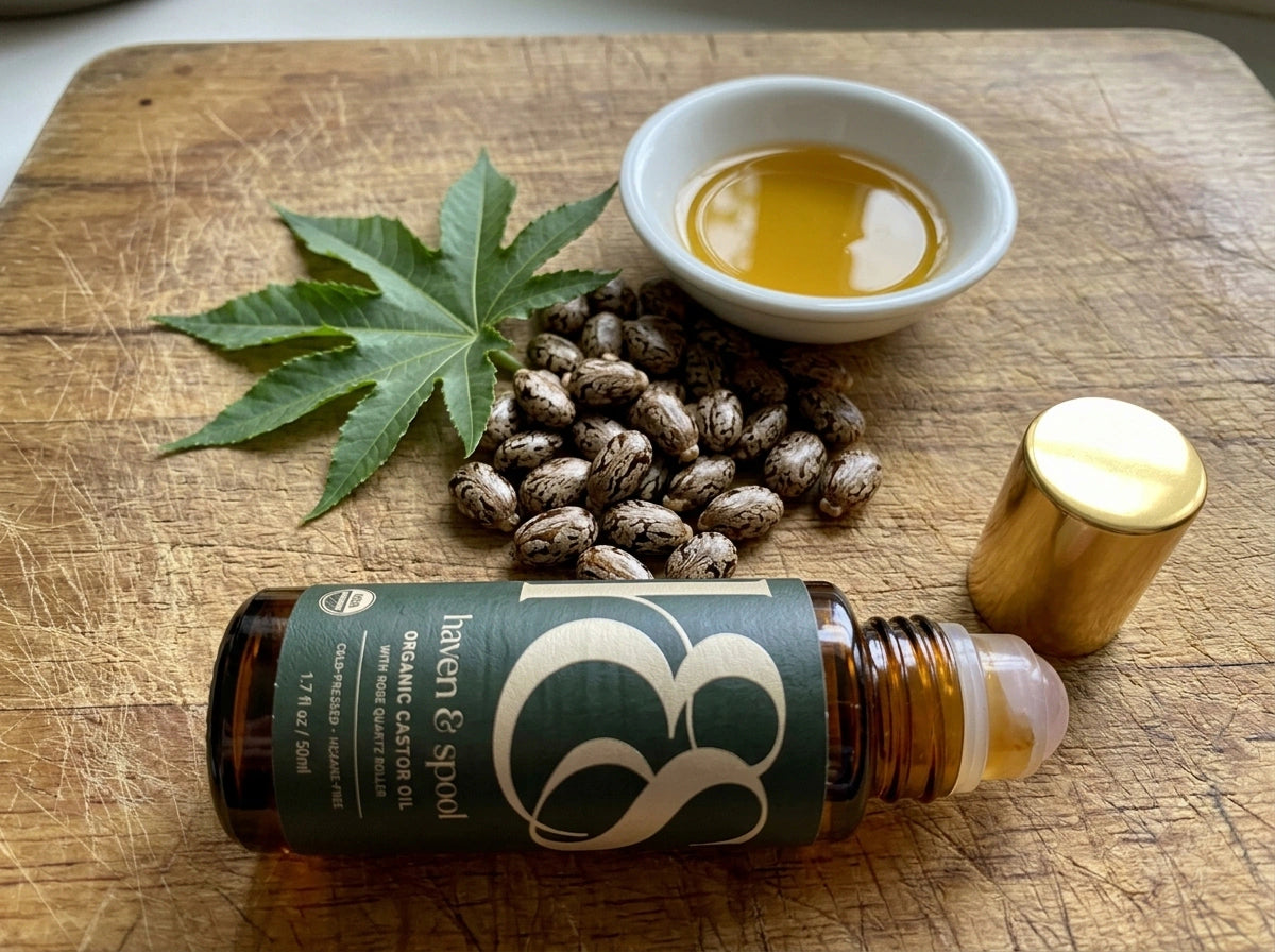 Castor beans, a castor leaf, a dish of the oil and the roll-on on a wooden board