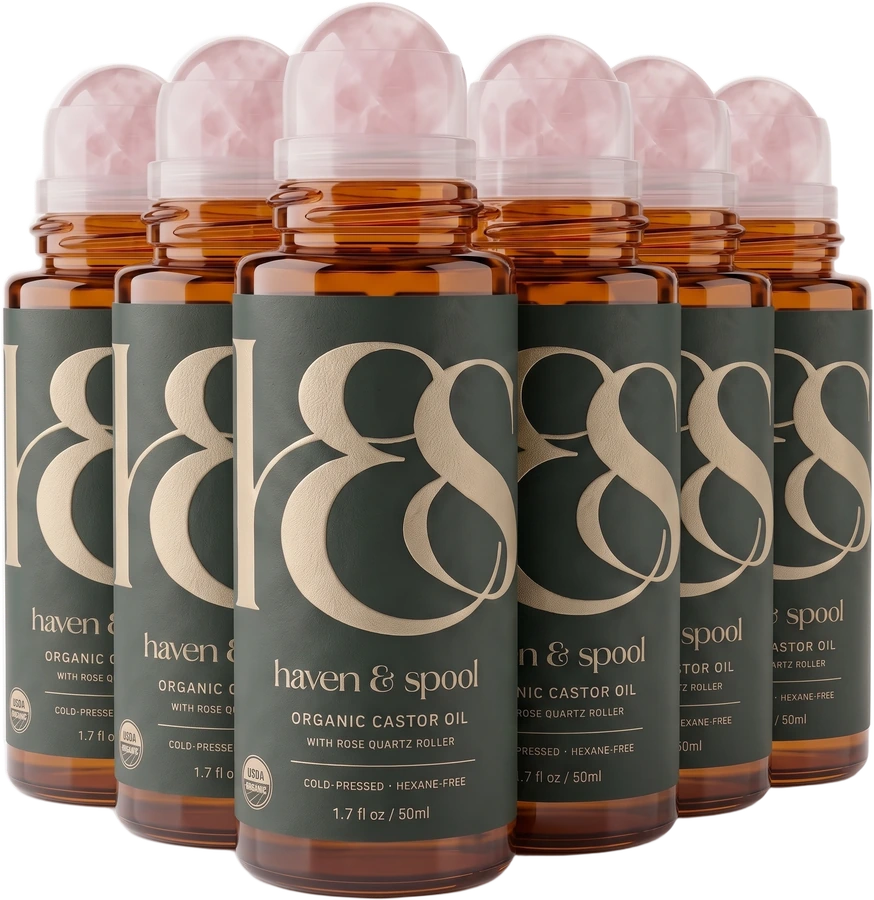 Six bottles of Haven & Spool organic castor oil with rose quartz rollers